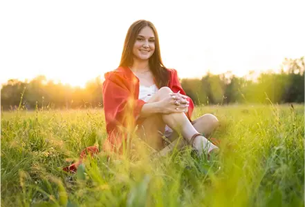 A woman sitting in the grass holding her phone.